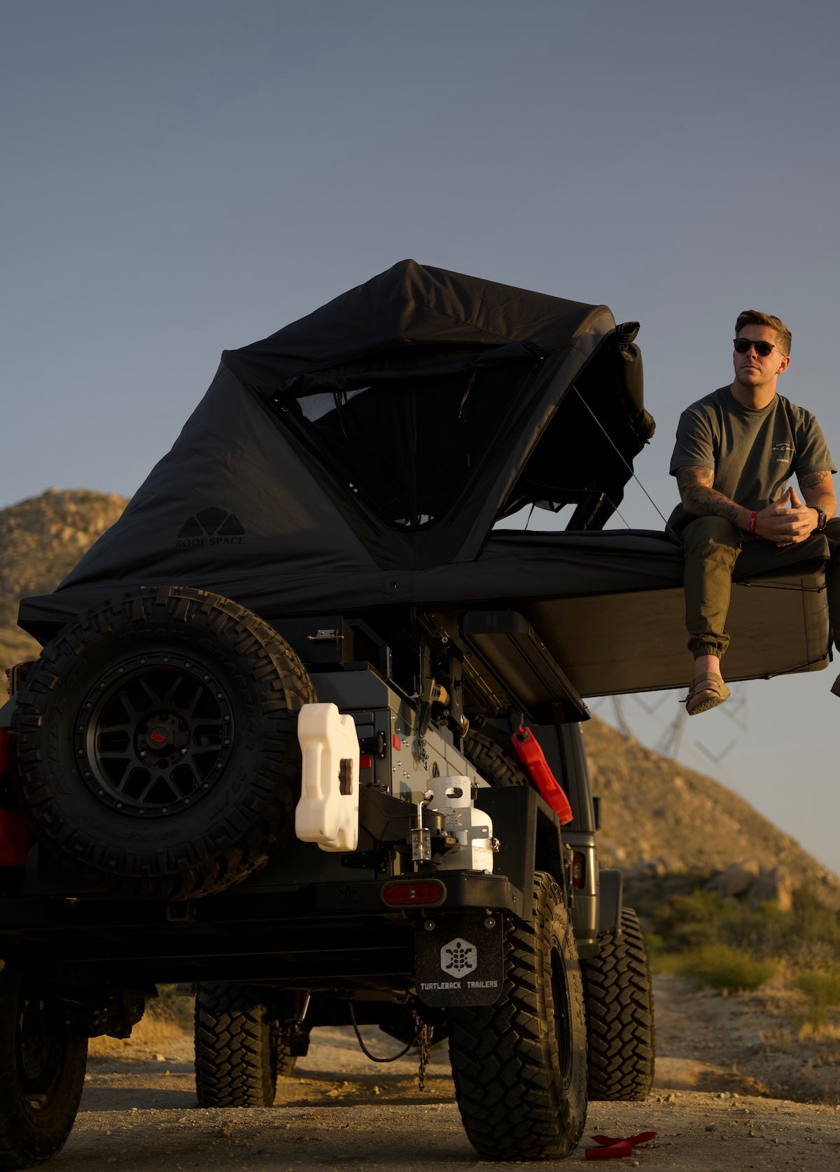 One person sitting on a open up Roof Space rooftop tent only supported by the integrated steel cables.